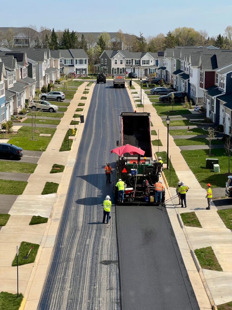 Asphalt paving crew laying fresh hot-mix on a community association street
